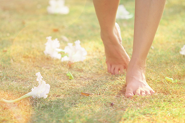Person walking across the grass with scattered white flowers on the ground